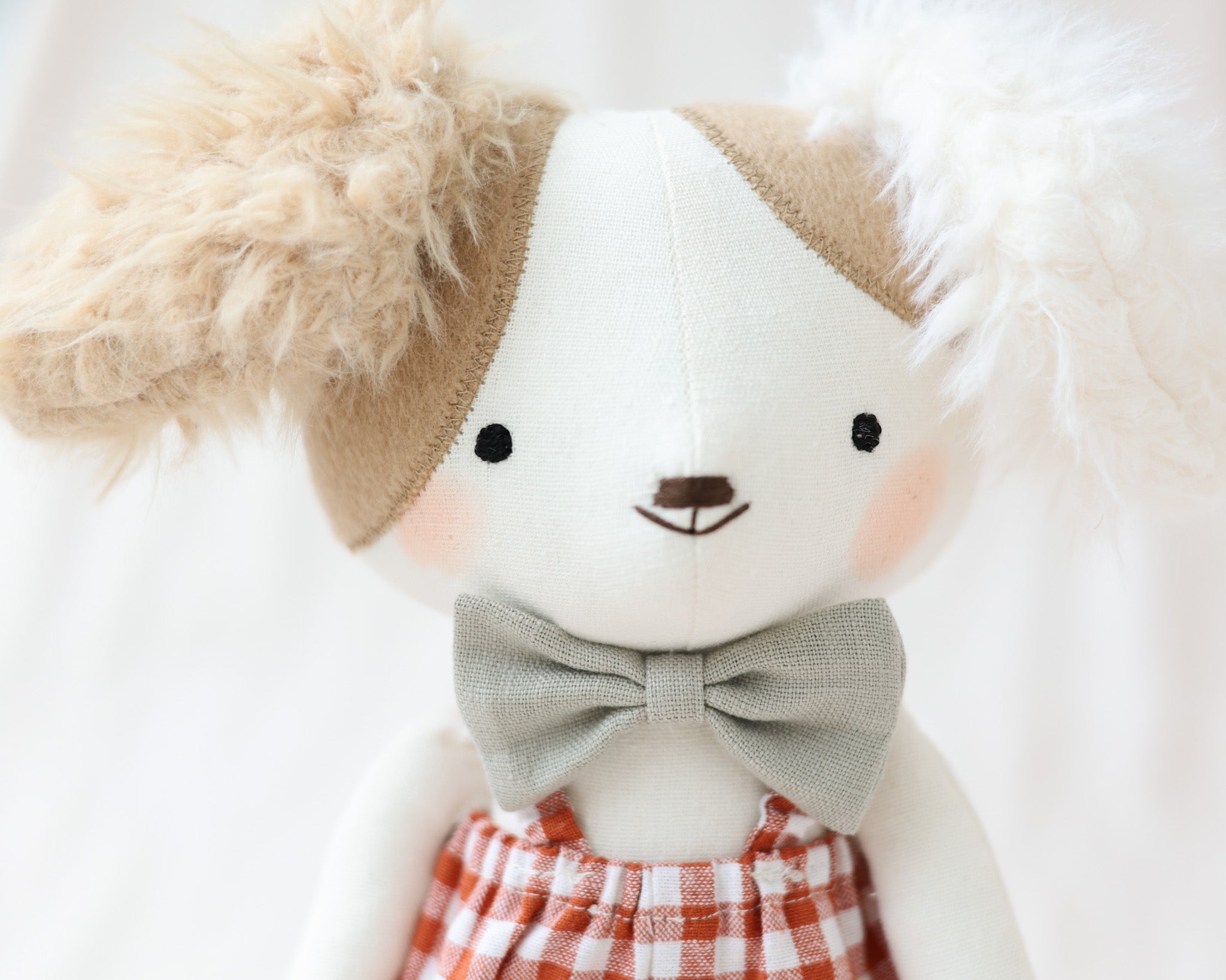 赤いギンガムチェックのジャンプスーツと蝶ネクタイを着た犬のぬいぐるみアルフォンス